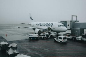Finnair airplane at Amsterdam airport during a gloomy day, with vehicles parked on the tarmac.