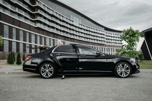 Senior businesswoman exiting a sleek black car in front of a modern building.