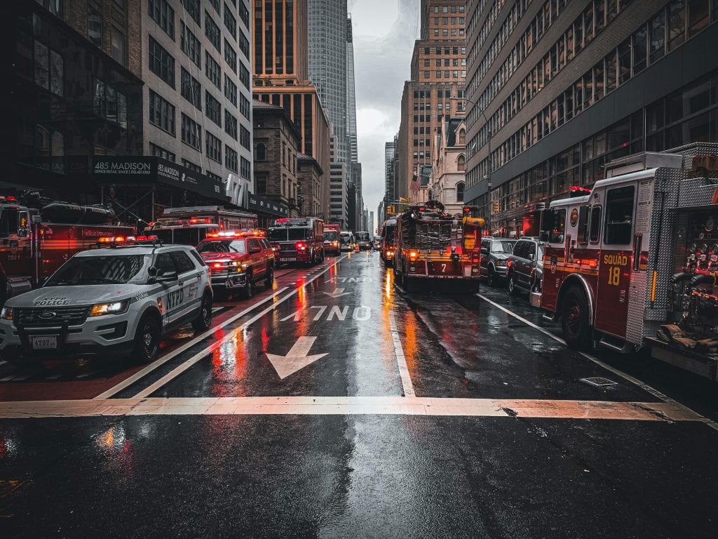 Firetrucks and police cars respond to an emergency on a wet street in New York City.