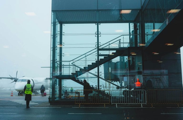 Passengers boarding an airplane at Riga Airport amidst fog, showcasing modern airport architecture.