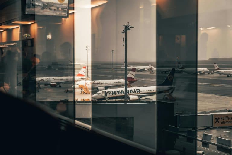 Car Service Blogs | Articles | News | Tips & Tricks | Video | FAQ | Information | Infograph. 36 Airplanes at a bustling airport with reflections of interiors in the window panes.