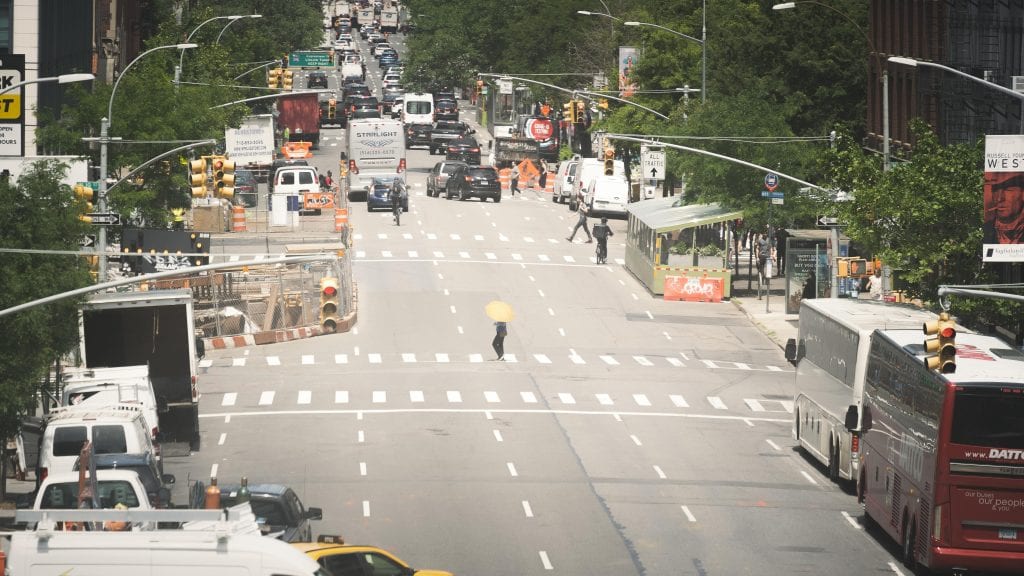 A bustling New York City street with cars and pedestrians on a sunny day.
