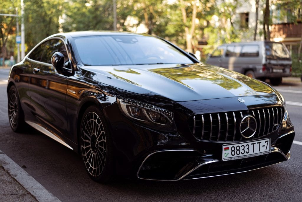 Elegant black luxury car parked on urban road, showcasing sleek design and polished exterior.