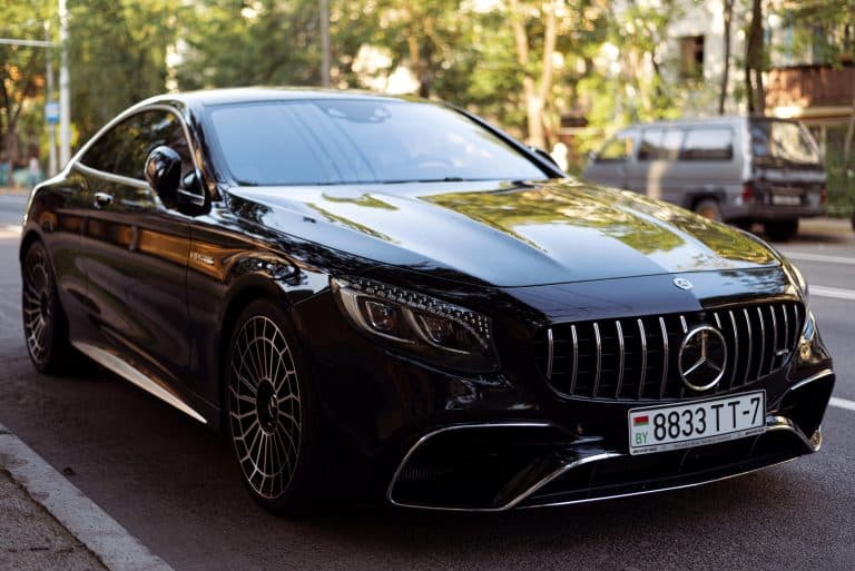 Elegant black luxury car parked on urban road, showcasing sleek design and polished exterior.