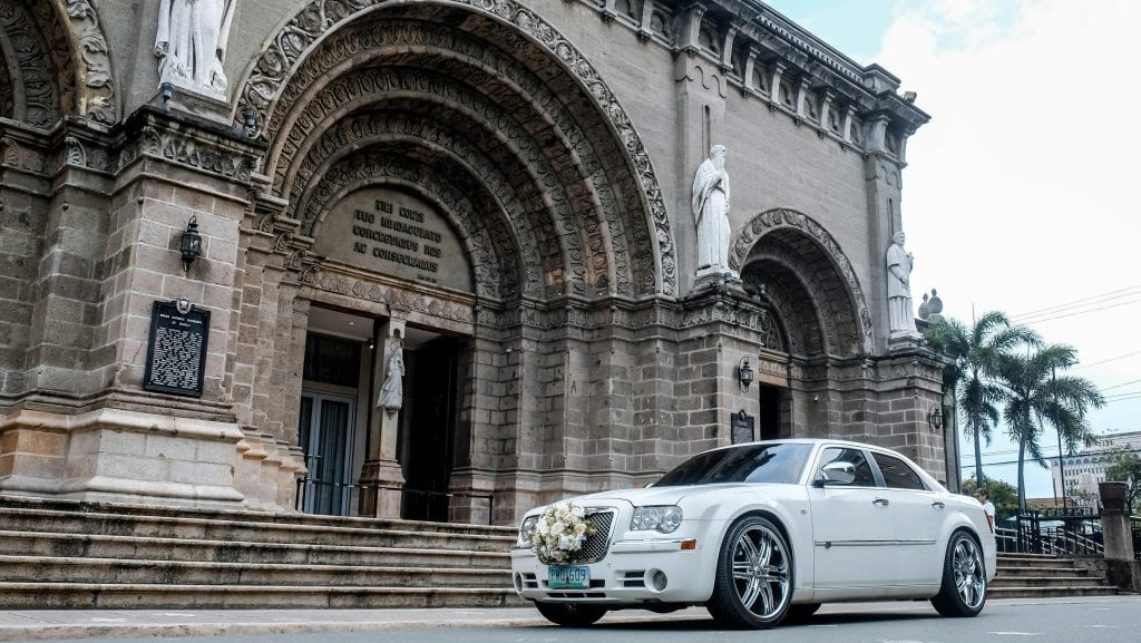 White wedding car with floral decoration parked outside a historic cathedral, Manila, Philippines.