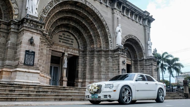 White wedding car with floral decoration parked outside a historic cathedral, Manila, Philippines.