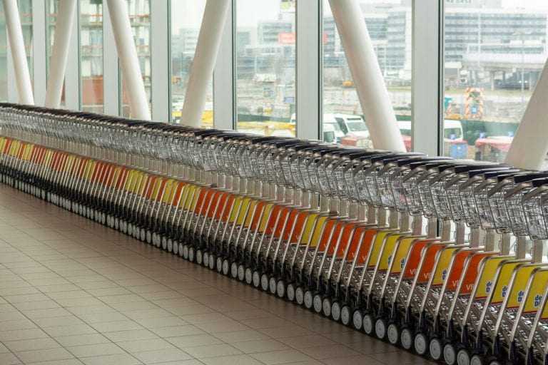 A row of luggage carts neatly lined up inside Schiphol Airport in Amsterdam.