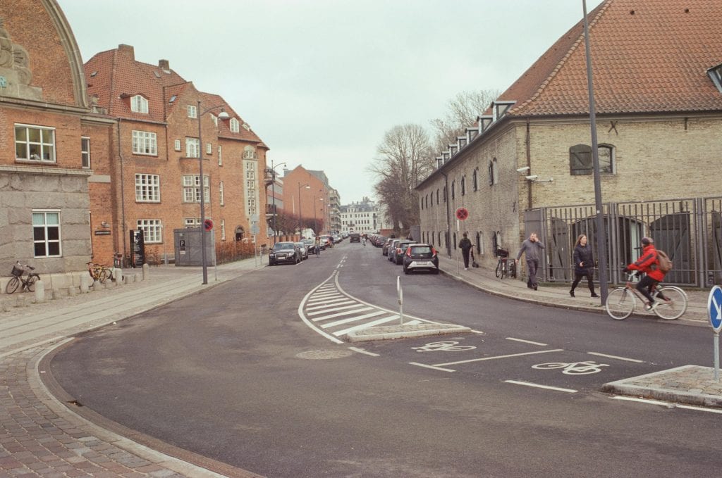 Charming street scene in Copenhagen with cyclists and historic architecture.