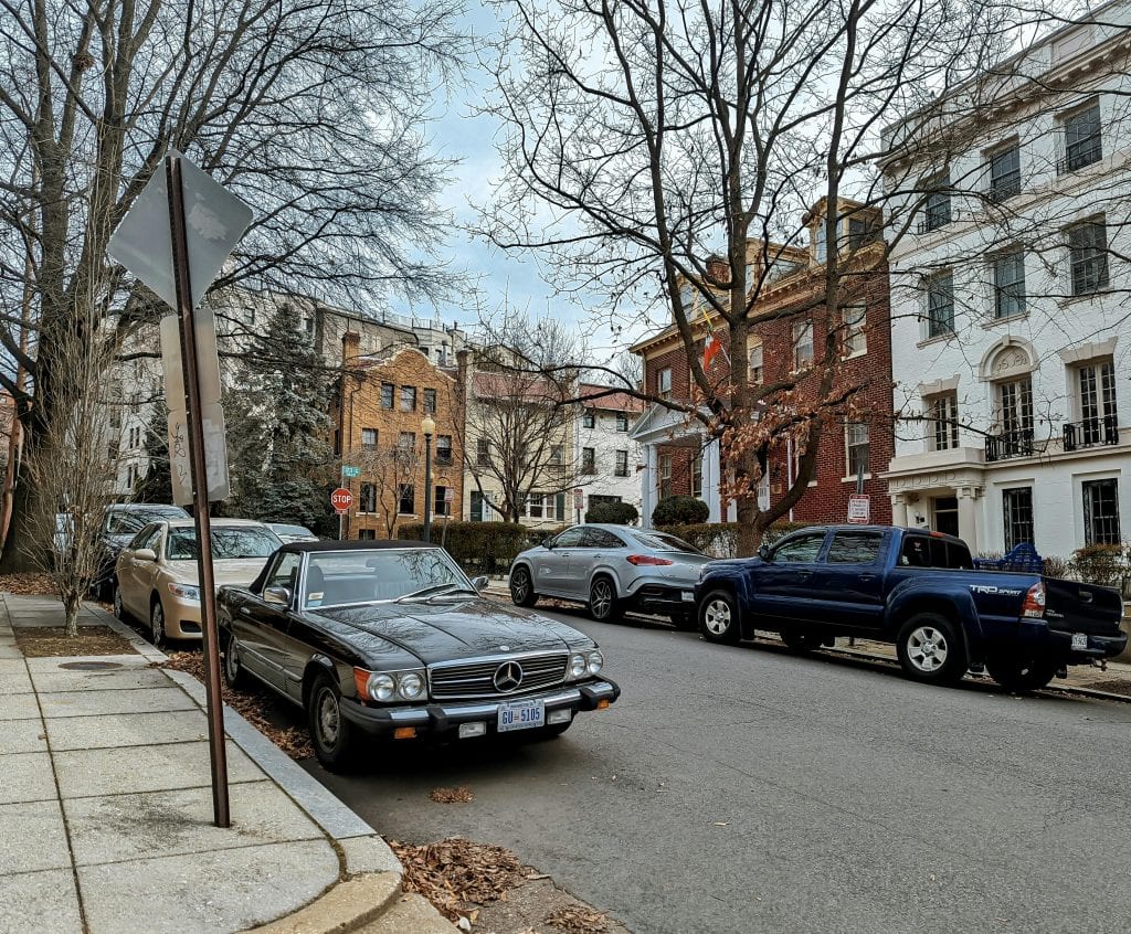 Street scene in Washington DC featuring classic cars parked under bare trees in autumn.