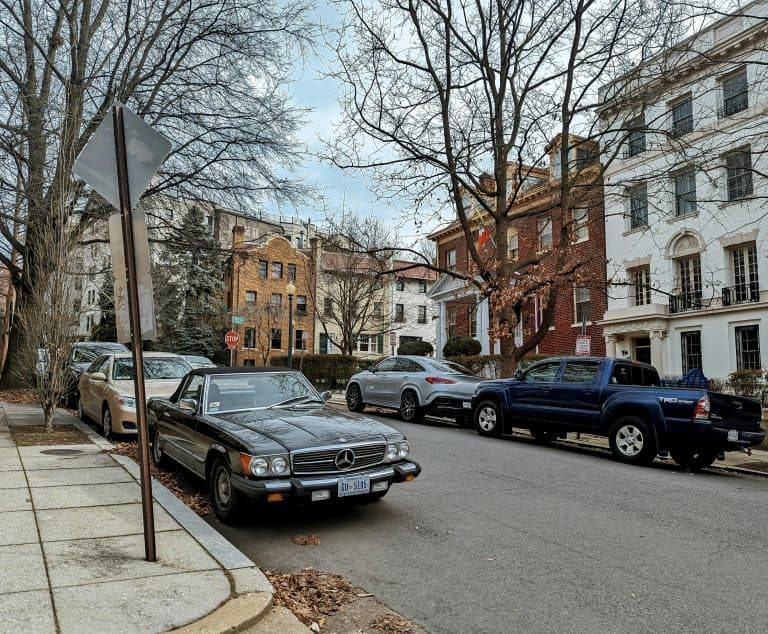 Street scene in Washington DC featuring classic cars parked under bare trees in autumn.