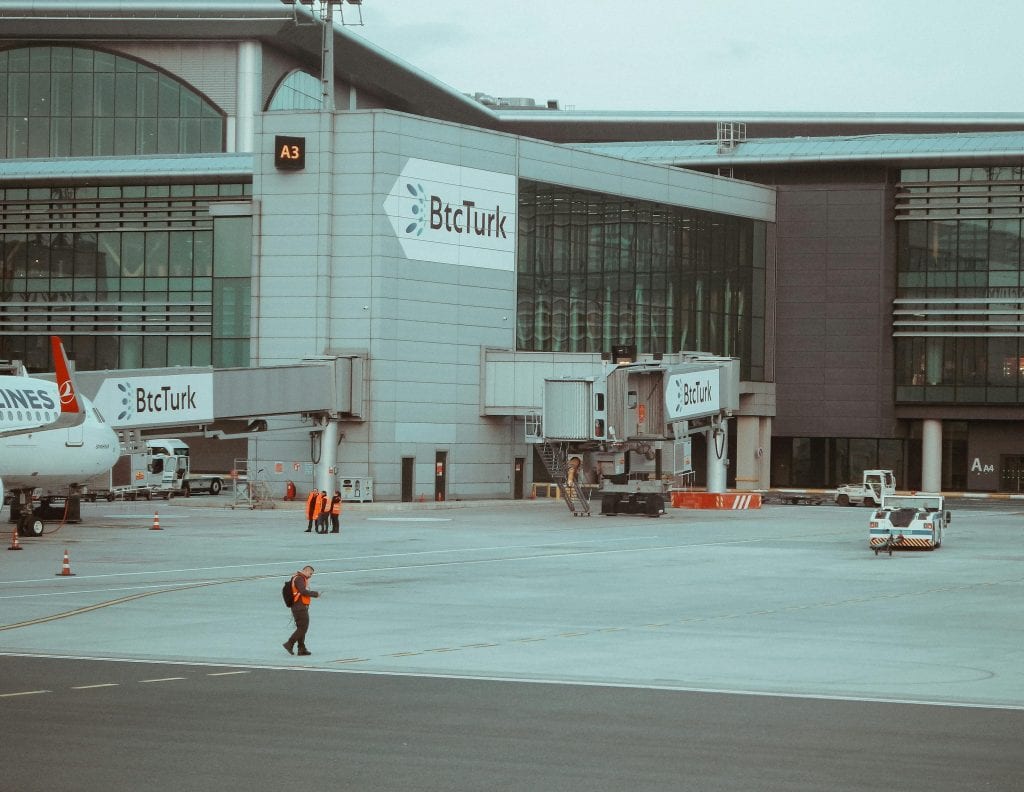 Istanbul airport terminal with BtcTurk branding and ground staff in action.