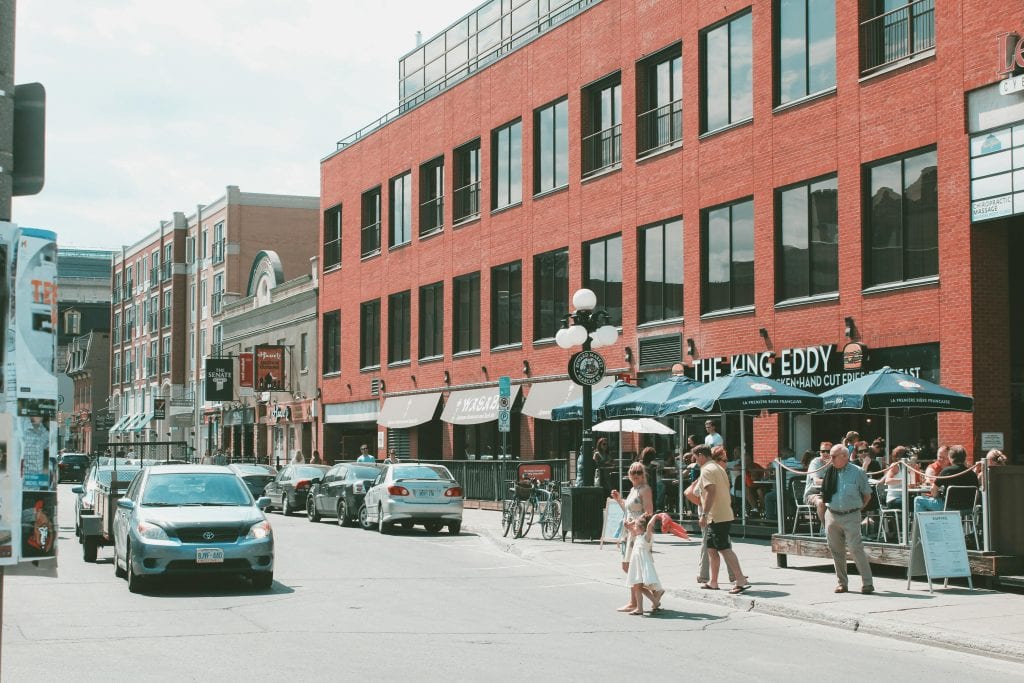 Vibrant street life in downtown Ottawa with cars, pedestrians, and outdoor cafes on a sunny day.