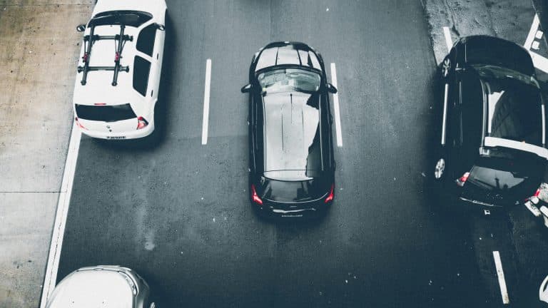 New York Blogs | Articles | News | Tips & Tricks | Video | FAQ | Information | Infograph. 33 Overhead view of cars on an urban road with wet asphalt, showcasing city transportation.