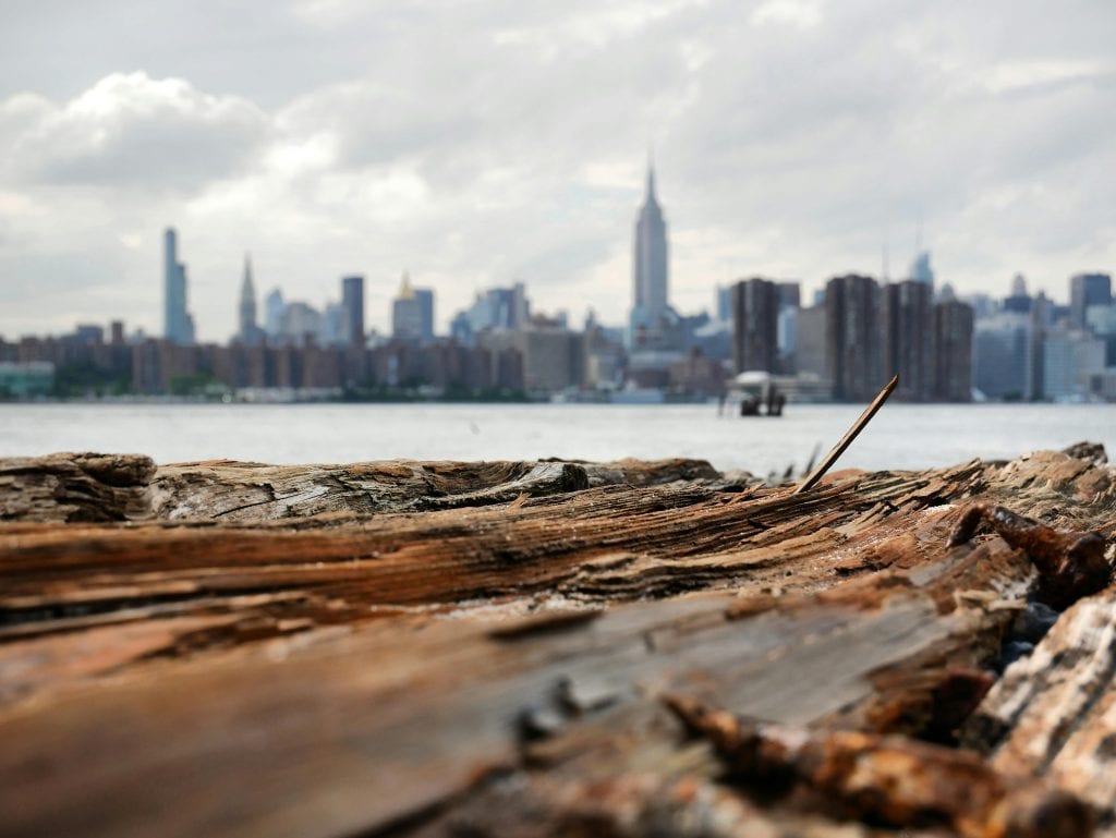 Rustic wood foreground with New York City skyline in the background under cloudy sky.