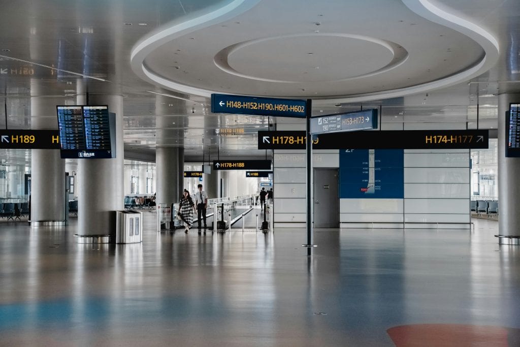 Spacious interior view of a modern airport terminal in Shanghai with signage and travelers.