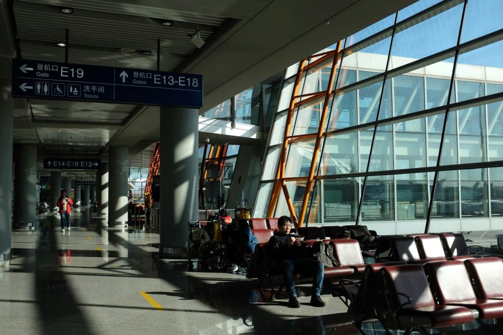 Bright modern airport terminal with seated passengers and directional signs.