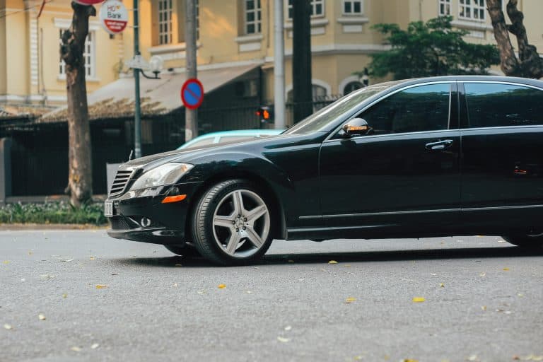 A black luxury sedan parked on an urban street near a bank building, showcasing elegance and style.