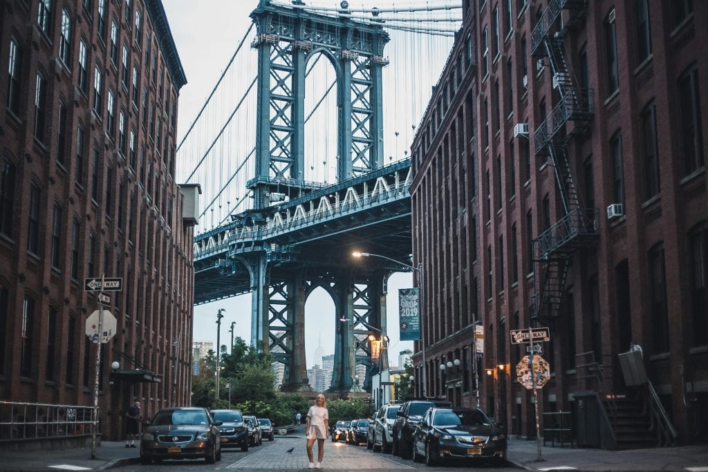 Iconic view of the Manhattan Bridge framed by urban buildings in Brooklyn, NY.