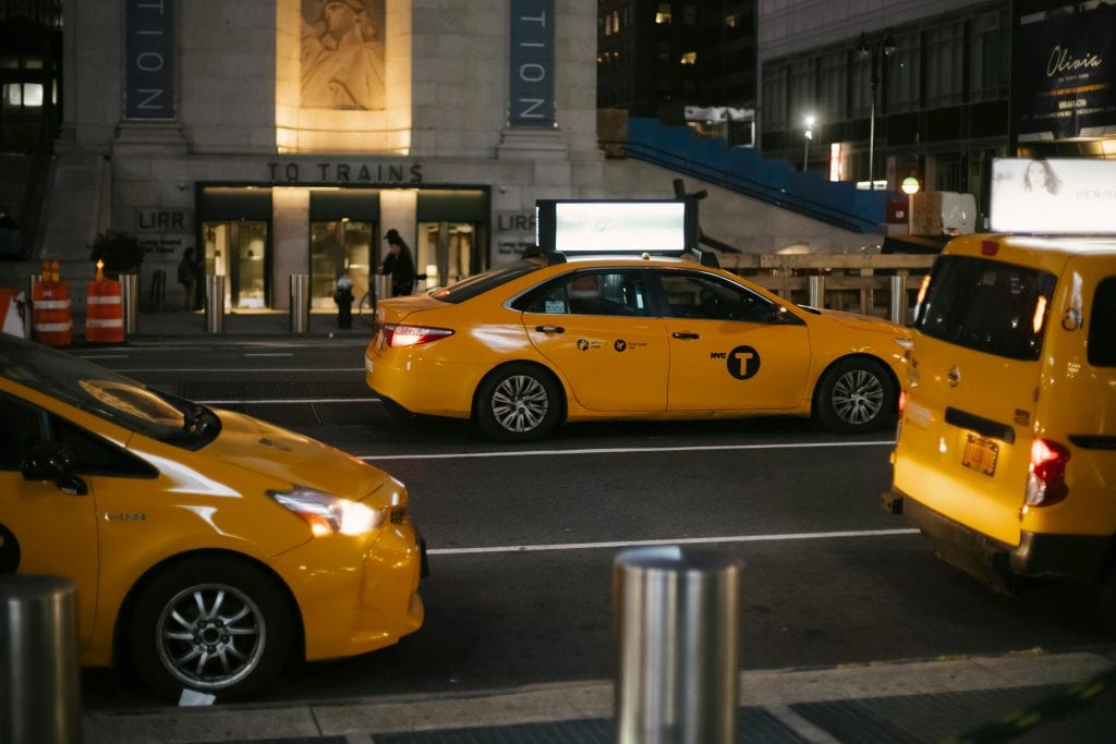 From above of contemporary shiny yellow cabs riding on asphalt roadway in New York at night