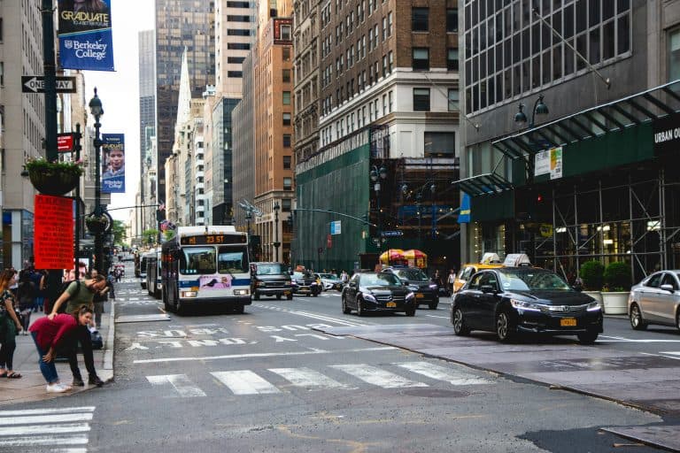 A vibrant New York City street scene with traffic, skyscrapers, and pedestrians crossing.