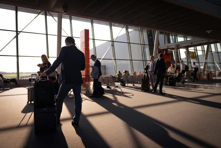 Airport Transfer Blogs | Articles | News | Tips & Tricks | Video | FAQ | Information | Infograph. 1 Travelers in a bustling airport terminal with carry-on luggage waiting for departure.