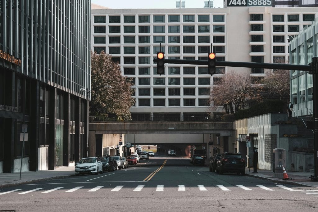 Cityscape view of an urban street with traffic lights, vehicles, and tall buildings on a clear day.