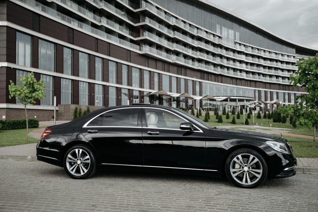 Elegant black sedan parked in front of a modern architectural building, showcasing luxury and style.