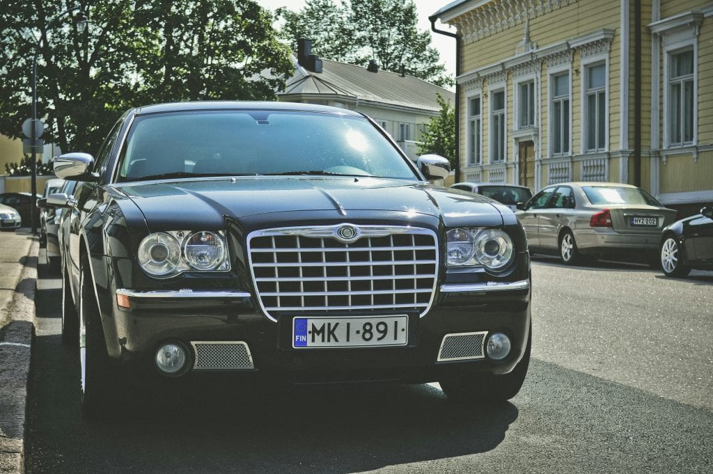 A sleek black car parked on a sunny street in Hamina, Finland, showcasing luxury and elegance.