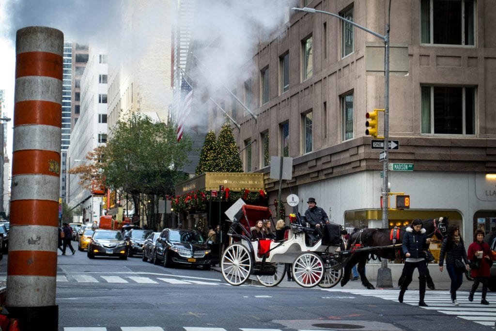 Eco Friendly Car Service from JFK to Manhattan in 2026: Your No-Nonsense Green Transfer Guide That Actually Delivers 9 Busy New York City street with horse carriage and Christmas decorations.