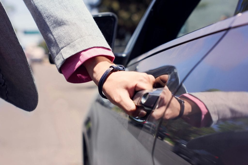 Close-up image of a hand opening a car door, highlighting business and transit themes.