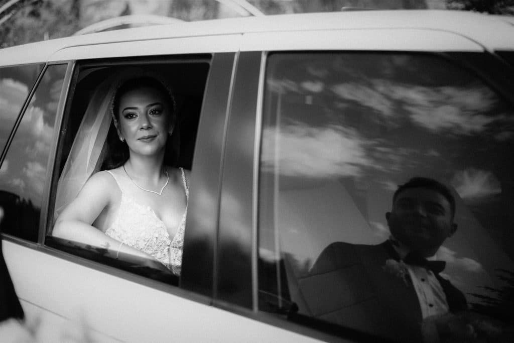 Reliable Wedding Limousine New York: 6 Honest Facts for 2026 19 A bride and groom share a reflective moment in a car, captured in black and white.