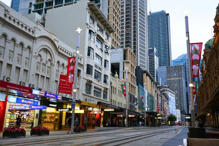 Places & Attractions Blogs | Articles | News | Tips & Tricks | Video | FAQ | Information | Infograph. 1 A bustling Sydney street scene featuring shops, historic buildings, and skyscrapers under twilight.