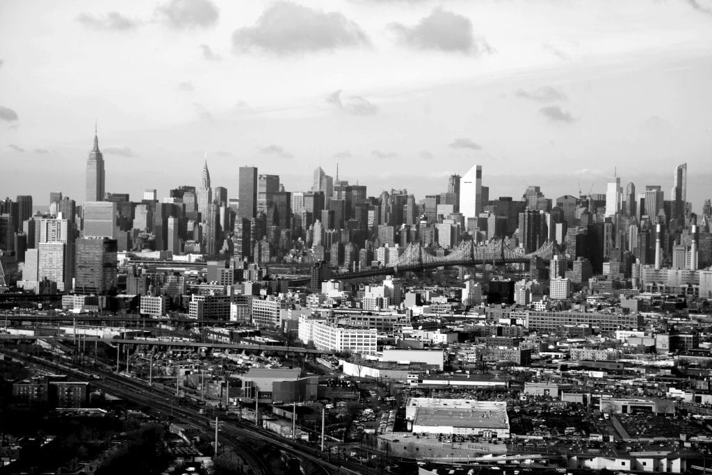 Black and white aerial view of New York City's iconic skyline with skyscrapers and bridges.