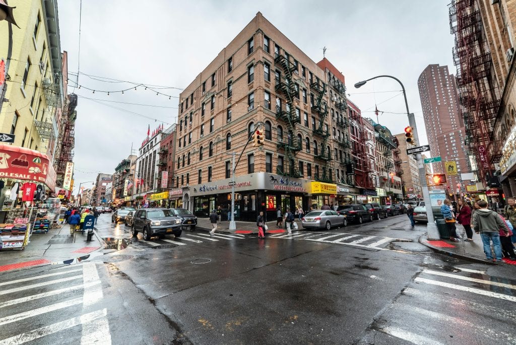 Affordable Town Car Service New York City: 7 Honest Facts for 2026 7 Bustling Chinatown in New York City after rain, featuring iconic architecture and lively atmosphere.