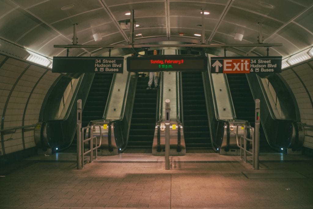 View of escalators in a modern New York City subway station during the evening.