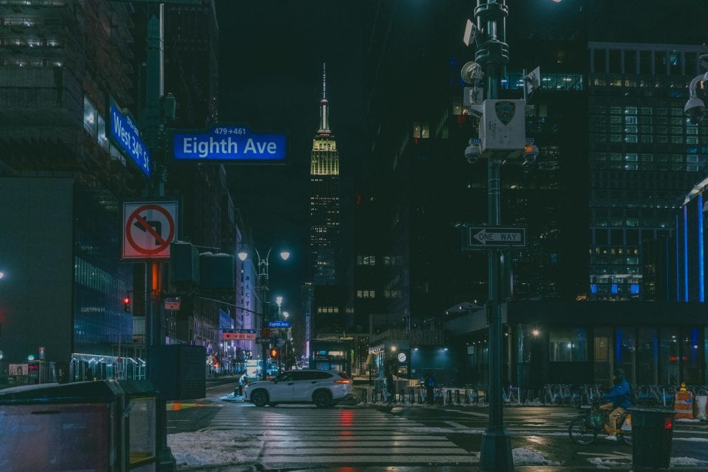 Atmospheric night scene of Eighth Avenue with the Empire State Building in New York City.