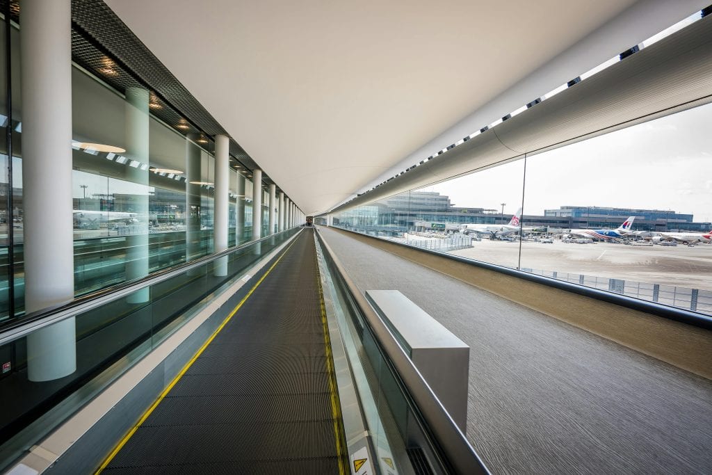 Taxi at JFK Airport in 2026: The Real Costs, Chaos, Hidden Fees, and Why Smart Travelers Choose Fixed-Rate Black Car Service Instead 5 Sleek interior view of a Japanese airport terminal with a moving walkway and airplanes visible outside.