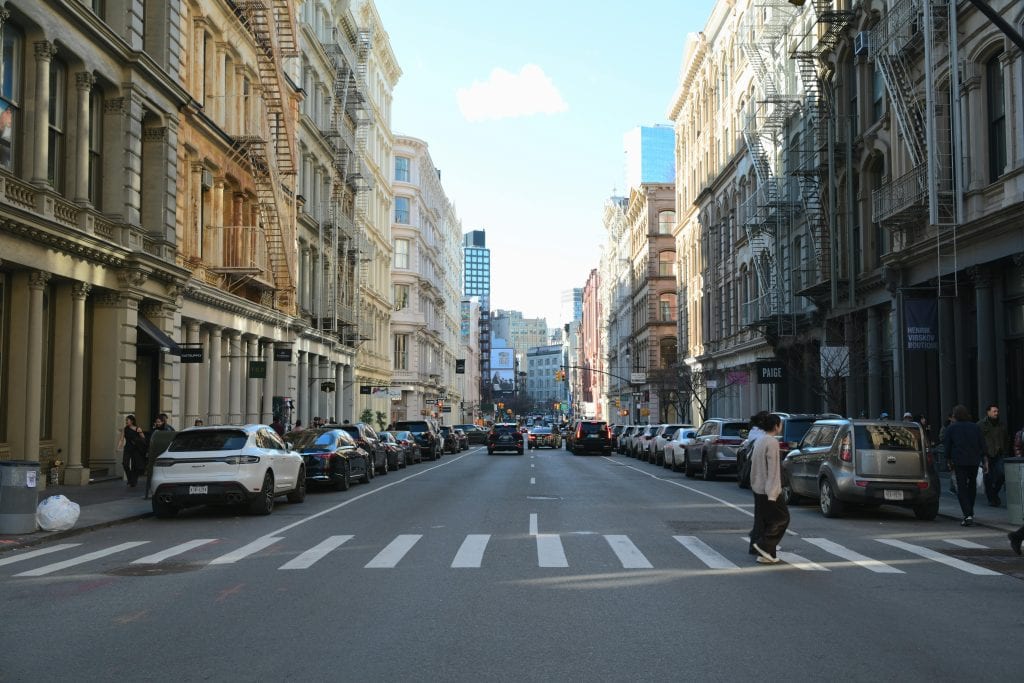 How Much Is a Town Car Service in NYC in 2026: Real Family Pricing, TLC Rules & Why Fixed-Rate Black Cars Beat the Chaos 15 Serene moment on a bustling SoHo street in NYC, featuring classic architecture.