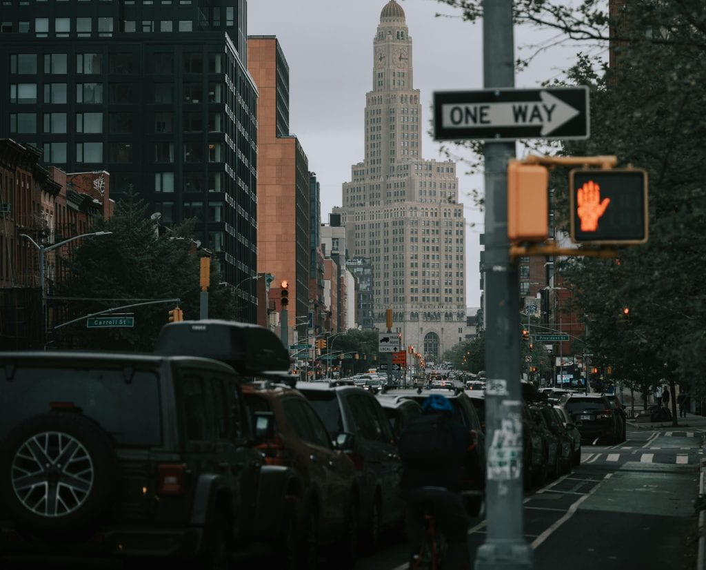 View of a bustling Brooklyn street with cars and iconic skyscraper in New York City.