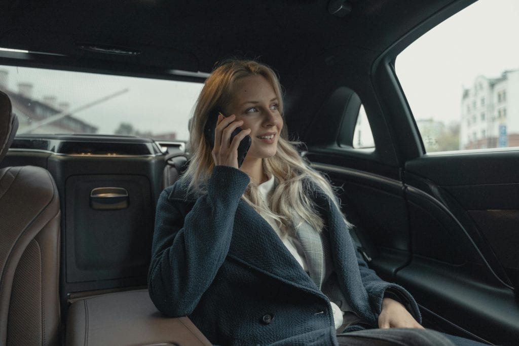 How Much Is a Limo from LaGuardia to NYC in 2026: Real Prices, Brutal Truths & Why Fixed-Rate Black Cars Actually Save Your Sanity 13 Businesswoman talking on phone while sitting in a luxury car, portraying professionalism and leadership.