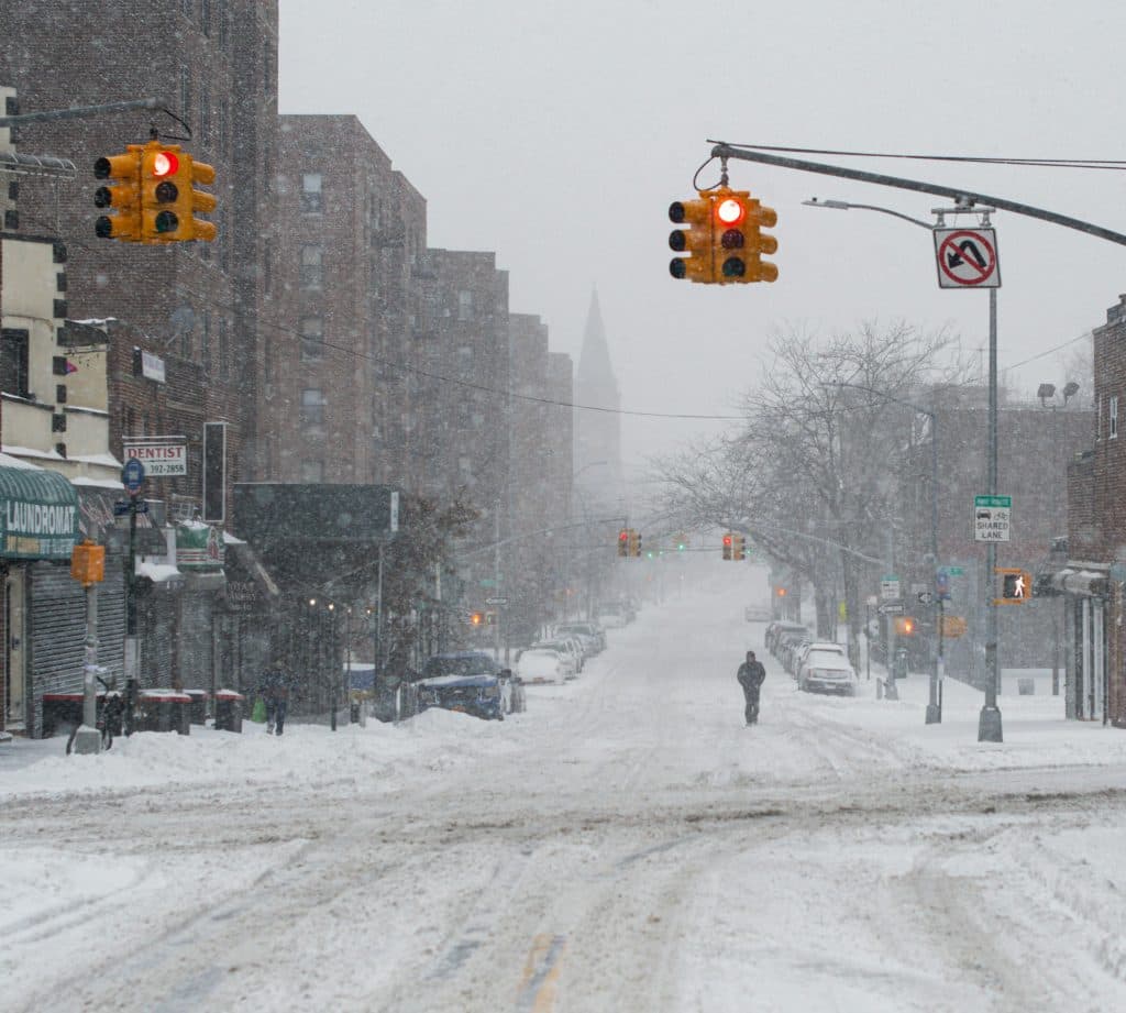 Queens Limo Services for Events: 5 Honest Things Need to Know in 2026 1 A snow-covered urban street with traffic lights and a lone pedestrian, capturing the essence of winter in the city.