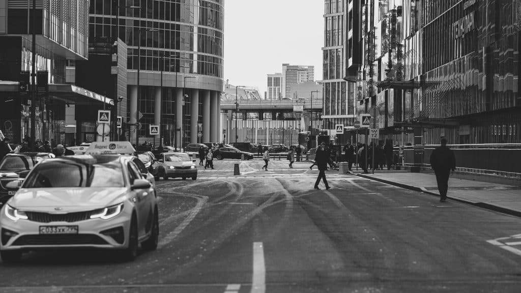 Busy city street scene in Moscow with cars, pedestrians, and modern architecture.