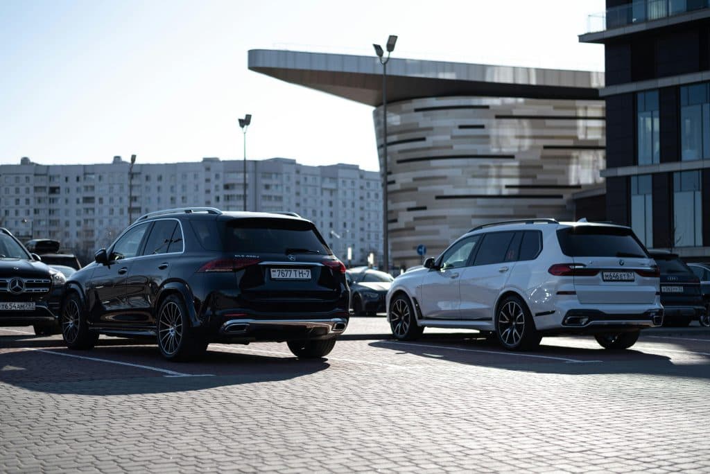 Private Car Service New York for Events in 2026: The Ultimate Stress-Free Luxury Guide for Weddings, Galas, Corporate Gatherings & More 3 Two luxury SUVs parked in an urban setting with modern buildings in the background.