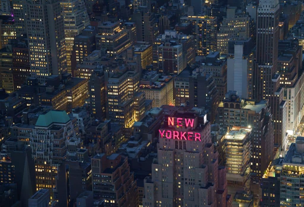 A captivating aerial shot of New York City featuring the illuminated New Yorker Hotel.