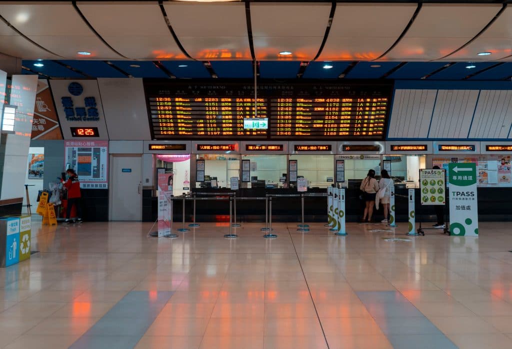 Interior of a train station with a digital timetable and ticket counters.