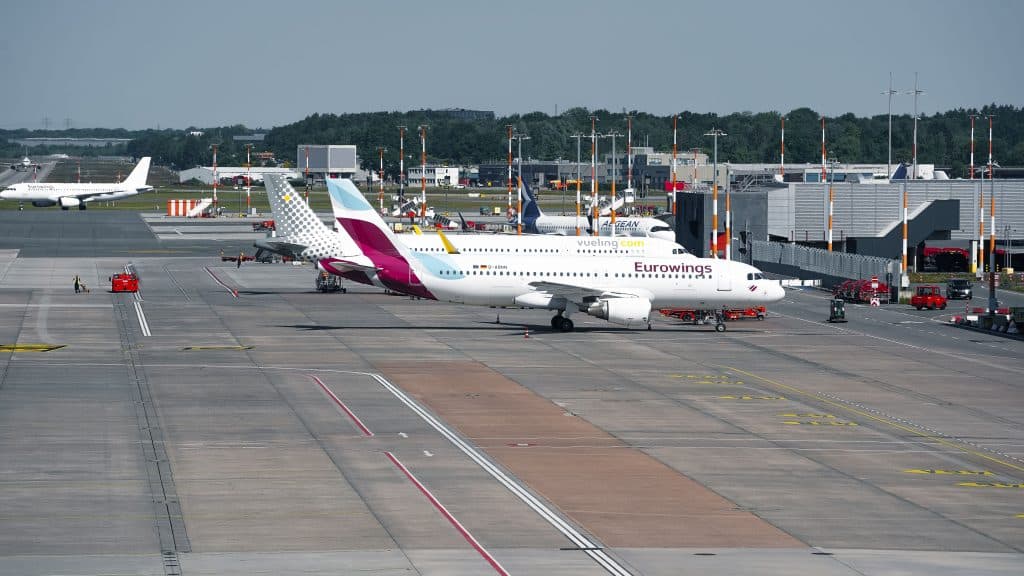 Wide-angle view of a bustling airport in Hamburg featuring Eurowings aircraft on the taxiway.