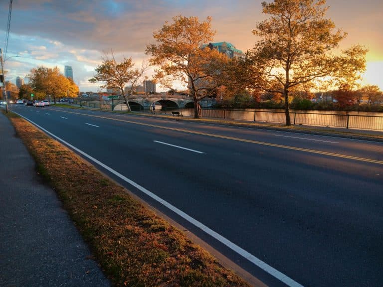 Car Service Blogs | Articles | News | Tips & Tricks | Video | FAQ | Information | Infograph. 22 A serene sunset view of an empty road lined with autumn trees beside a river.