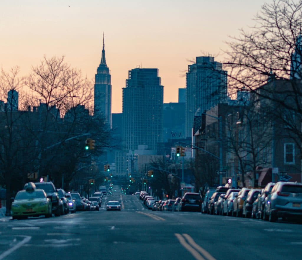 Capture of New York City skyline at dusk featuring the Empire State Building and urban street view.