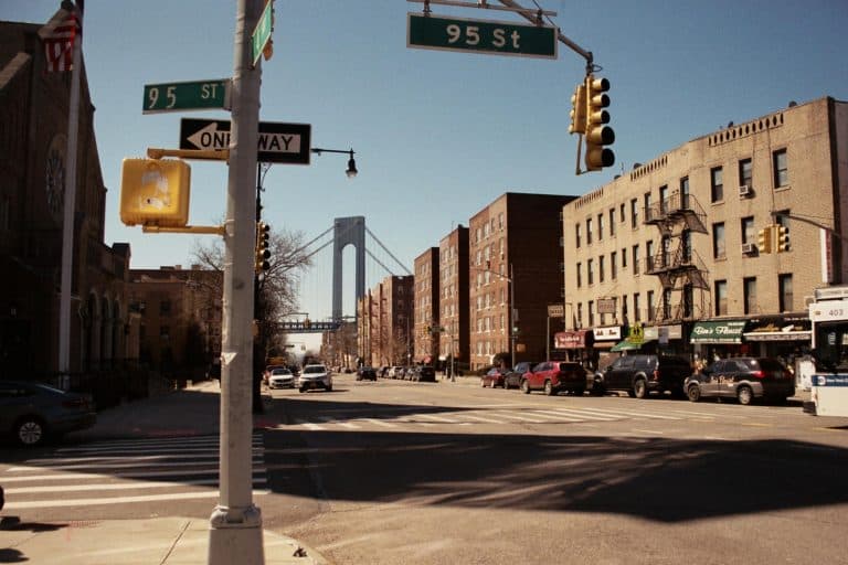 City street view with buildings, traffic lights, and a bridge under a clear sky.