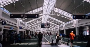 Spacious airport terminal with moving walkway and travelers, showcasing modern architecture.